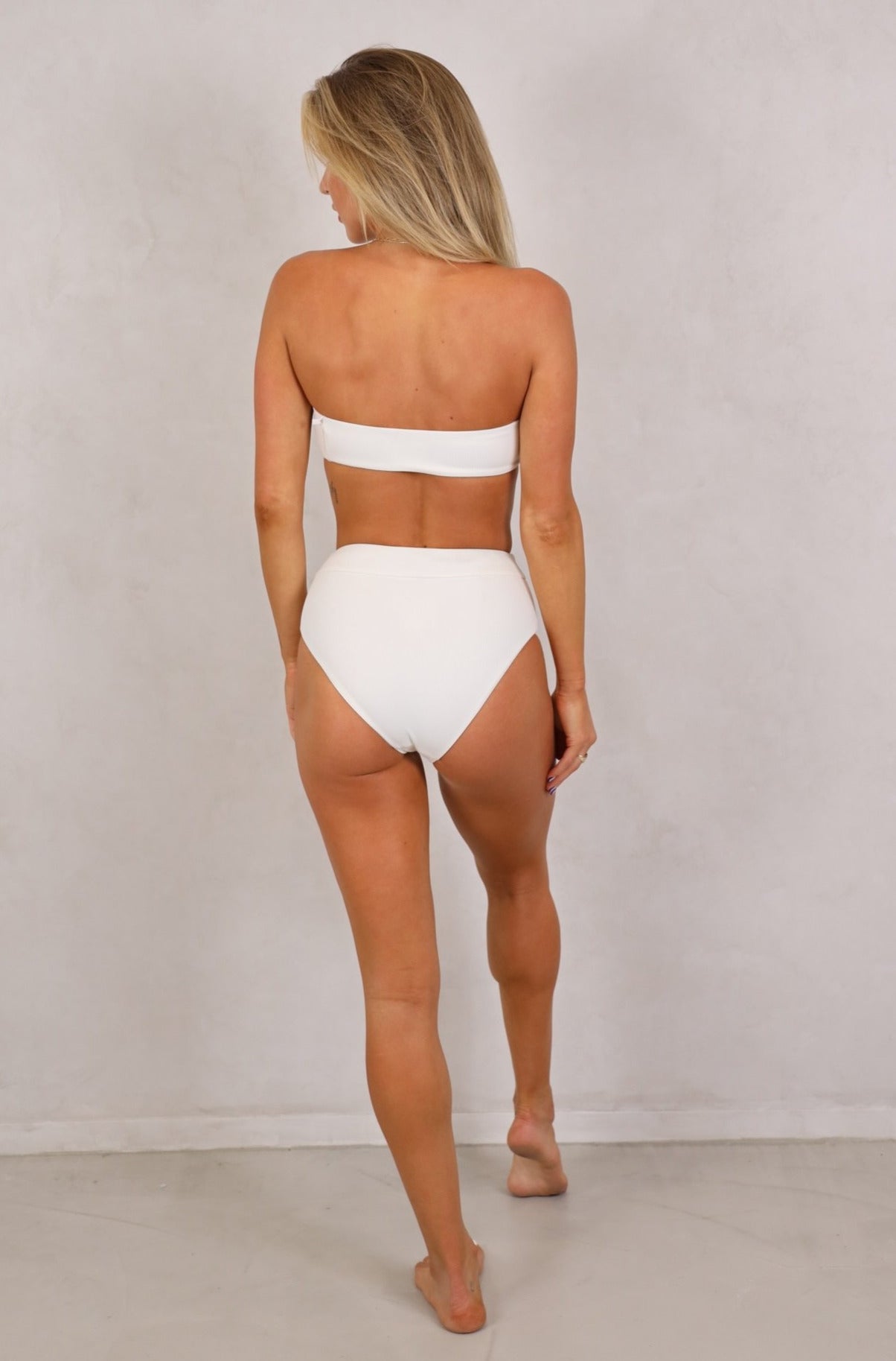 Bandeau strapless top. Removable padding. Removable tie up knot top.Shop women's high waist seamless ribbed swimwear.Shop Women's Swimwear online.Women's Bikinis and swimsuits. White ribbed swimwear. High waist bikini bottoms. Full coverage. White bikini bottoms. Fabric: Ribbed / Easy to care / Stretchy / 87% Nylon / 13% Spandex